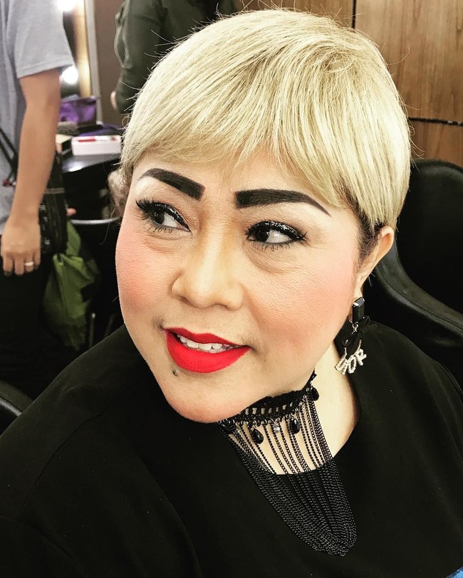 Tampil dengan lipstik bold warna merah yang kontras dengan rambut pirangnya. Statement earring dari Dior pun menambah nyentrik gayanya. Foto: Instagram/@triretnoprayudati_nunung