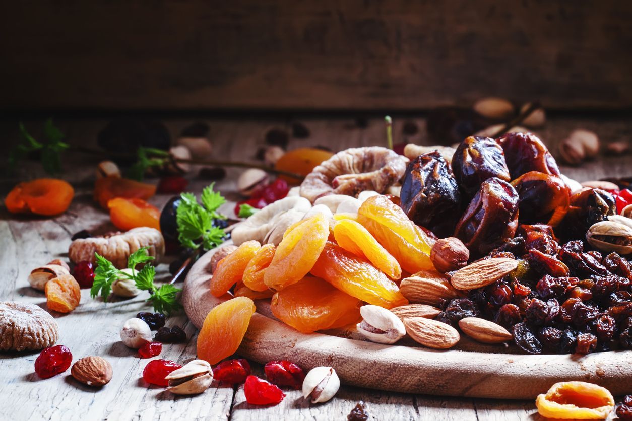 Dried apricots, dates, raisins and various nuts, vintage wooden background, selective focus