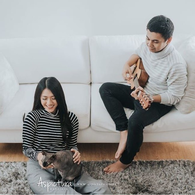 Raditya Dika dan Annisa Aziza memilih konsep simpel seperti berada di rumah dalam foto prewedding indoor mereka. Hewan peliharaan kesayangan pun ikut dilibatkan di sini. Keduanya tampil serasi dengan busana motif garis. Foto: Instagram