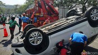 Petugas dibantu warga berusaha mengevakuasi sopir dan mobil naas tersebut.
