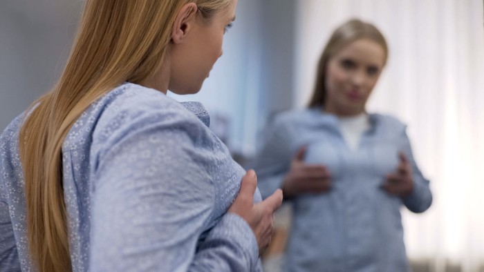 ilustrasi operasi payudara Portrait of female doctor choosing mammary prosthesis with her patient over white background.