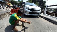 Seorang anak memandu mobil melintasi jembatan.