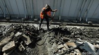 Pekerja menghancurkan coran yang akan dibuat pedestrian.