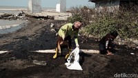 Secara manual, mereka memasukkan minyak ke dalam karung yang sudah dicampur dengan pasir pantai.