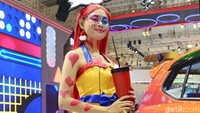 Seorang gadis Daihatsu mengenakan pakaian bertema pop art berpose di samping salah satu mobil pabrikan Jepang tersebut.