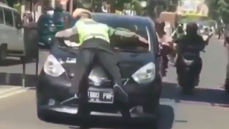 Polisi nemplok di kap mobil. Foto: Screenshot Lambe Turah Polisi nemplok di kap mobil. Foto: Screenshot Lambe Turah