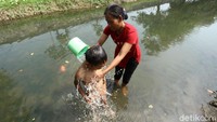 Seorang warga sedang memandikan anaknya di kali Kawasan Kabupaten Tangerang, Jumat (26/7/2019).