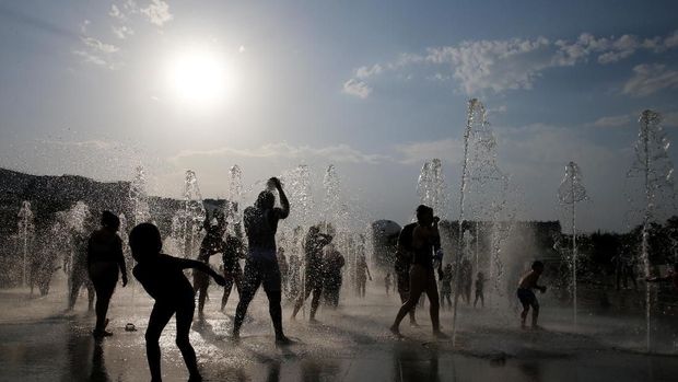 People are silhouetted as they cool off in water fountains in a park as hot summer temperatures hit Paris, France, July 2019 REUTERS/Pascal Rossignol
