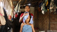 Seorang warga mengeringkan tubuh anaknya usai mandi di pinggiran kali di Kabupaten Tangerang.