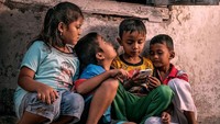 Potret anak-anak di Indonesia tengah asyik bermain permainan di ponsel. Istimewa/@recaear/Agora Images via Boredpanda.