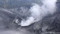 Asap tebal masih mencuat dari dasar kawah. Bau belerang pun bercampur dengan debu vulkanik yang berterbangan tertiup angin.
