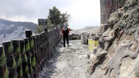 Seorang warga melintas di jalan yang masih diselimuti abu vulkanik Gunung Tangkuban Perahu.