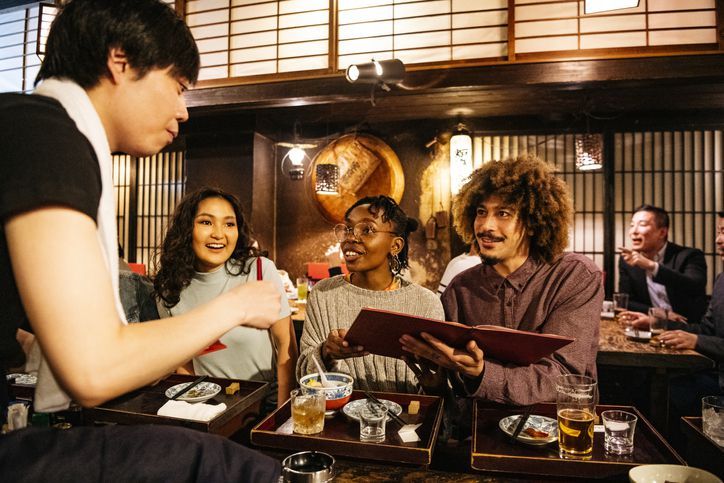 Hipster couple ordering food from menu in Japanese Izakaya, nightlife, decisions, cheerful