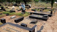 Pekerja menyirami rumput yang mulai mengering di areal makan TPU Tanah Kusir.