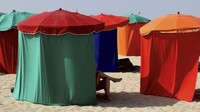 Di Deauville, Prancis, para wanita bersantai di pantai dengan suhu 38 derajat dengan menggunakan tenda seperti ini. (REUTERS/Kevin Coombs TPX IMAGES OF THE DAY)