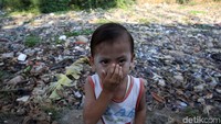 Seorang anak menutup hidung akibat bau tidak sedap dari Kali Pisang Batu.