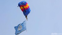 Penerjun payung melayang-layang sambil mengibarkan bendera TNI AL.
