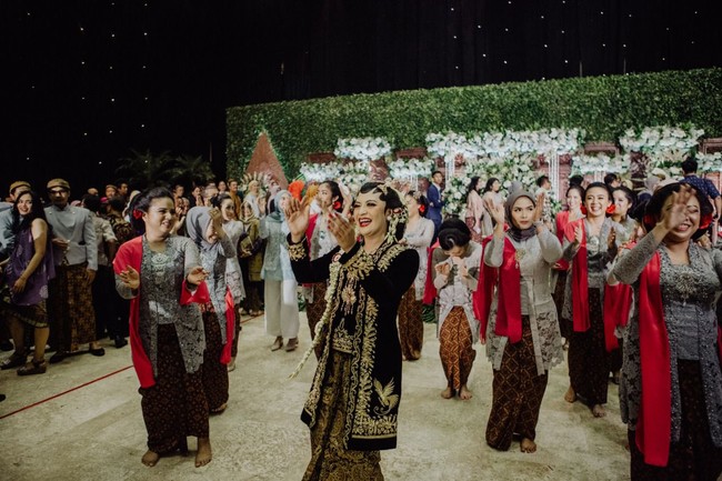 Aksi zumba flashmob yang berlangsung di pernikahannya itu sudah direncanakan oleh teman-teman sang pengantin wanita. Tak mau ketinggalan momen, Okti pun akhirnya turun ke pelaminan dan ikut zumba bareng para among tamu dan tamu pernikahan. Foto: dok. @maknafoto