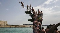 Masih di Brittany, Prancis, para kawula muda mengantre untuk lompat ke dalam kolam di Saint-Malo. (Valery HACHE/AFP)