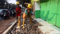 Petugas melakukan pelebaran trotoar.