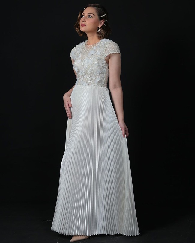 Juga berbusana putih, ada Mona Ratuliu dengan gaun sarat detail karya Ernesto Abram. Meskipun berwarna putih polos, gaun tak terlihat membosankan karena perpaduan aksen lipit, bordiran serta ornamen bunga tiga dimensi. Foto: Instagram/@monaratuliu