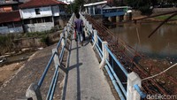 Warga melintasi jembatan di atas Bendungan Cisadane.