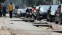 Pejalan kaki melintas diantara proyek pembangunan trotoar.