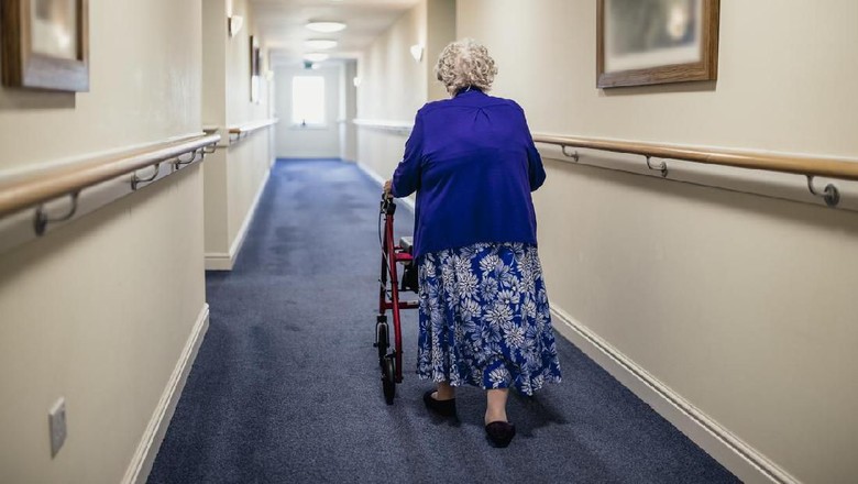 Ilustrasi Nenek 107 Tahun A senior woman walking down a corridor with the assistance of a walker. view from rear