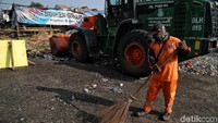 Petugas membersihkan sampah di tempat penampungan sampah di sekitar kandang hewan kurban.