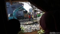 Sampah dikeruk dan diangkut menggunakan truk.