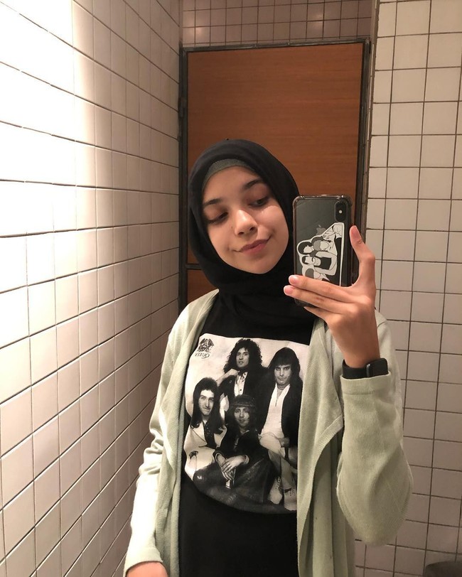  Beberapakali terlihat memakai kaus dari band Queen, Isabel Azhari berpose selfie di depan cermin dengan mengenakan kaus bergambar para personel band favoritnya itu. Isabel yang populer di Instagram dengan followers lebih dari 9.800 itu memadukannya dengan outer abu-abu dan hijab polos berwarna hitam. Foto: dok. instagram @isabel.azhari