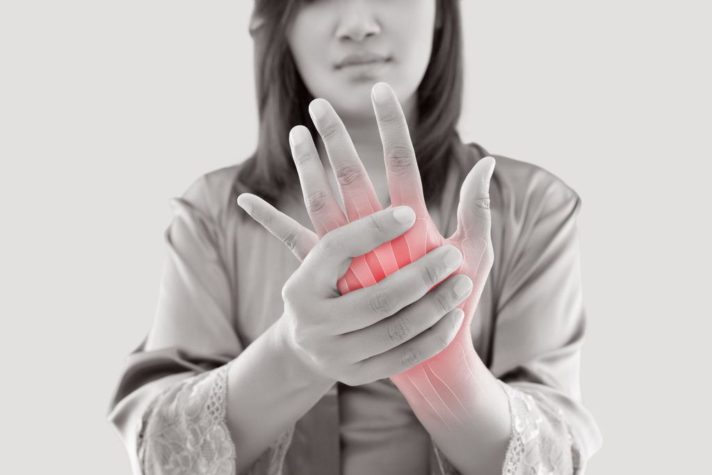 Asian woman suffering from pain in bone against gray background, Concept with hand arthritis grimace in pain