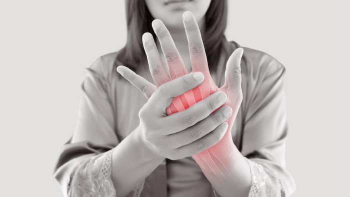 Asian woman suffering from pain in bone against gray background, Concept with hand arthritis grimace in pain
