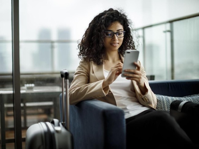 Smiling african-american business woman at work talking on phone and taking notes, sitting at her working place in office, copy space