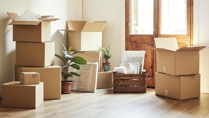 Full length shot of an attractive young woman stacking boxes while moving house