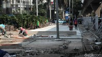 Sejumlah pekerja tengah menyelesaikan pengerjaan pelebaran trotoar di Jalan Satrio, Kuningan, Jakarta Selatan.