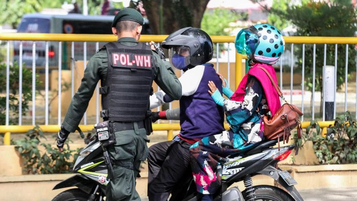 Petugas Wilayatul Hisbah (Polisi Syariat Islam) memakaikan kain sarung kepada warga memakai celana pendek saat terjaring razia penertiban hukum syariat islam di Lhokseumawe, Aceh, Senin (5/8/2019). Razia syariat Islam itu menjaring puluhan wanita memakai pakaian ketat dan pria memakai celana pendek yang tidak sesuai dengan hukum syariat, qanun nomor 11/2002 tentang akidah, ibadah dan syiar islam serta qanun nomor 6/2014 tentang hukum jinayat Aceh. ANTARA FOTO/Rahmad/foc.
