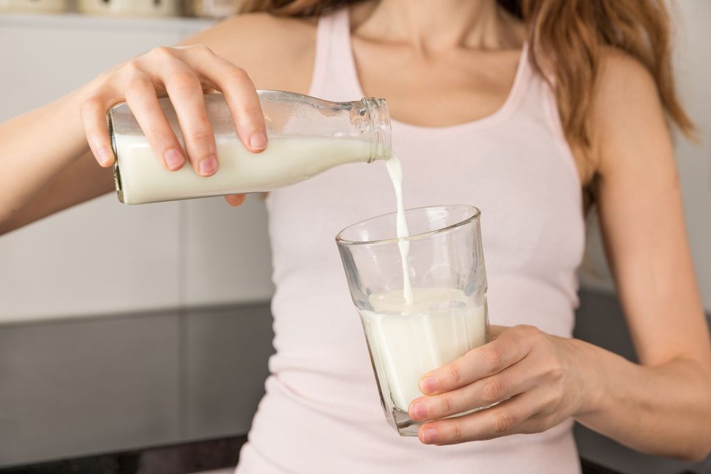 Glass of milk. Young woman with little braids drinking glass of milk in the morning at home