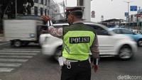 Polisi mengatur rombongan pengendara yang akan melintas karena traffic light tidak bekerja. Dia tampak sibuk.