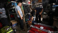Pegawai toko mengecek genset dan mencotohkan cara mengoperasikannya.