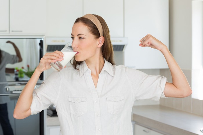 Minum Susu Glass of milk. Young woman with little braids drinking glass of milk in the morning at home