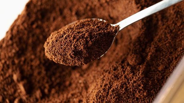 Ground coffee in spoon, natural coffee background, macro