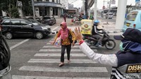 Petugas Dishub membantu warga menyeberang.