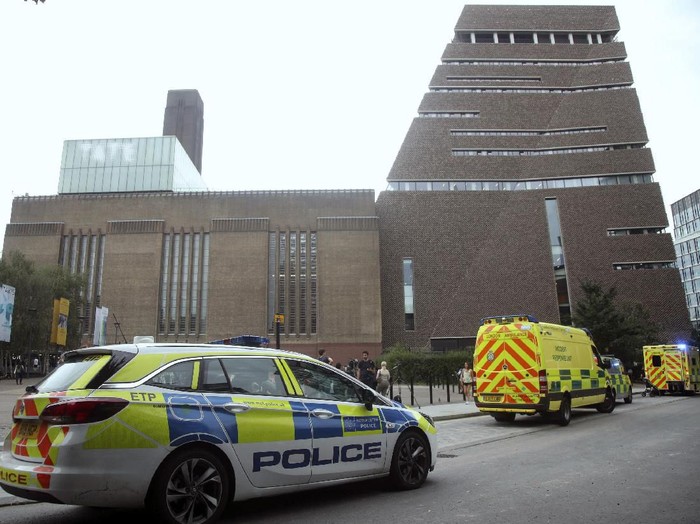 Emergency crews attending a scene at the Tate Modern art gallery, London, Sunday, Aug. 4, 2019. London police say a teenager was arrested after a child fell from height at the Tate Modern art gallery. The Metropolitan Police Service said on Twitter that the child was taken to a hospital in an air ambulance, adding We await an update on his condition. (Yui Mok/PA via AP)