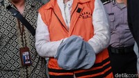 Simon Susilo menutupi borgol di kedua tangannya dengan topi.