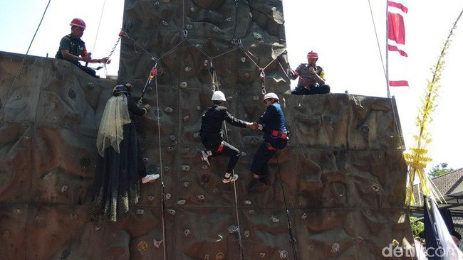 Saat hari pernikahannya, Nita yang berhijab memakai gaun pengantin muslimah dilengkapi dengan veil. Sedangkan Subandriyo mengenakan setelan jas hitam dan kemeja putih. Tak lupa keduanya memakai helm dan tali pengaman saat penghulu menikahkan mereka di ketinggian empat meter. Sang penghulu yang menikahkan mereka pun ikut panjat dinding lengkap dengan memakai helm dan tali pengaman. Foto: Eko Susanto/detikcom