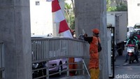 Satu per satu bendera merah putih dipasang oleh petugas PPSU di sepanjang Jalan Fatmawati, Jakarta.