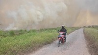 Warga melintas dengan kendaraanya saat terjadi kebakaran lahan gambut di Desa Pulau Semembu, Indralaya Utara, Ogan Ilir, Sumatra Selatan, Senin (5/8/2019). ANTARA FOTO/Ahmad Rizki Prabu.