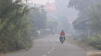 Pengendara sepeda motor melaju menembus kabut asap akibat Kebakaran Hutan dan Lahan (Karhutla) saat melintasi jalan Desa Pinem, Kecamatan Samatiga, Aceh Barat, Aceh, Selasa (6/8/2019). ANTARA FOTO/Syifa Yulinnas.