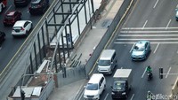 Pejalan kaki sedang menyeberang jalan di sekitar proyek pembangunan halte.